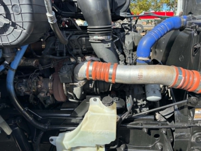 Kenworth T680 engine bay showing turbocharger, orange intake hoses, blue coolant hose, and radiator reservoir cap.