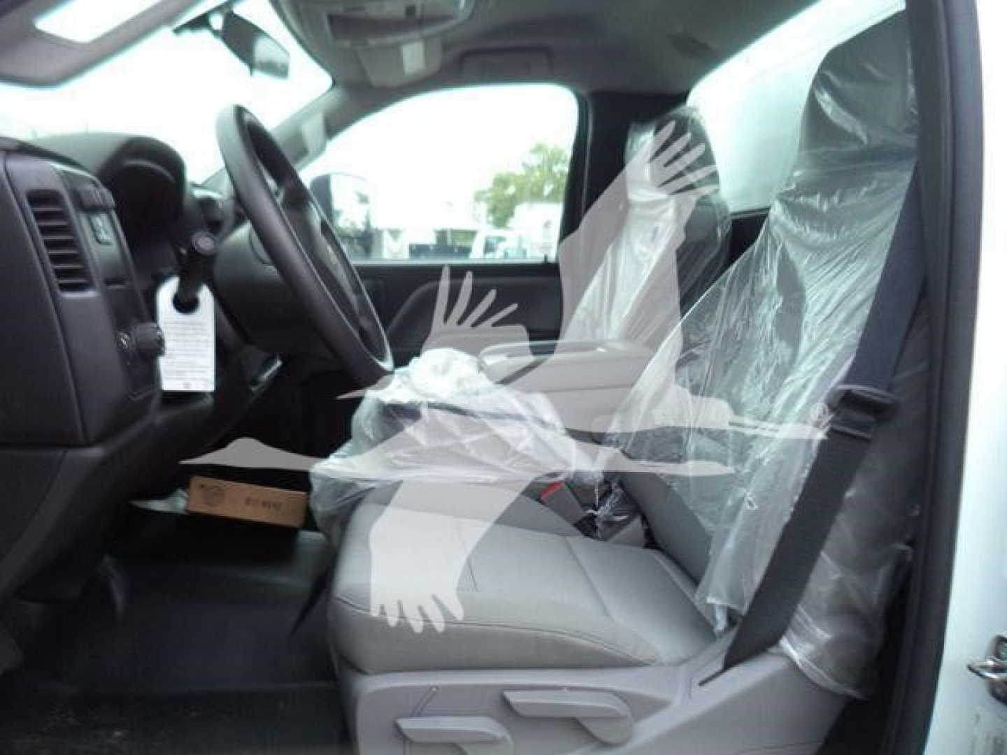 Truck cab interior of a 2023 Chevrolet Silverado 6500HD showing front seats wrapped in plastic and dashboard details.