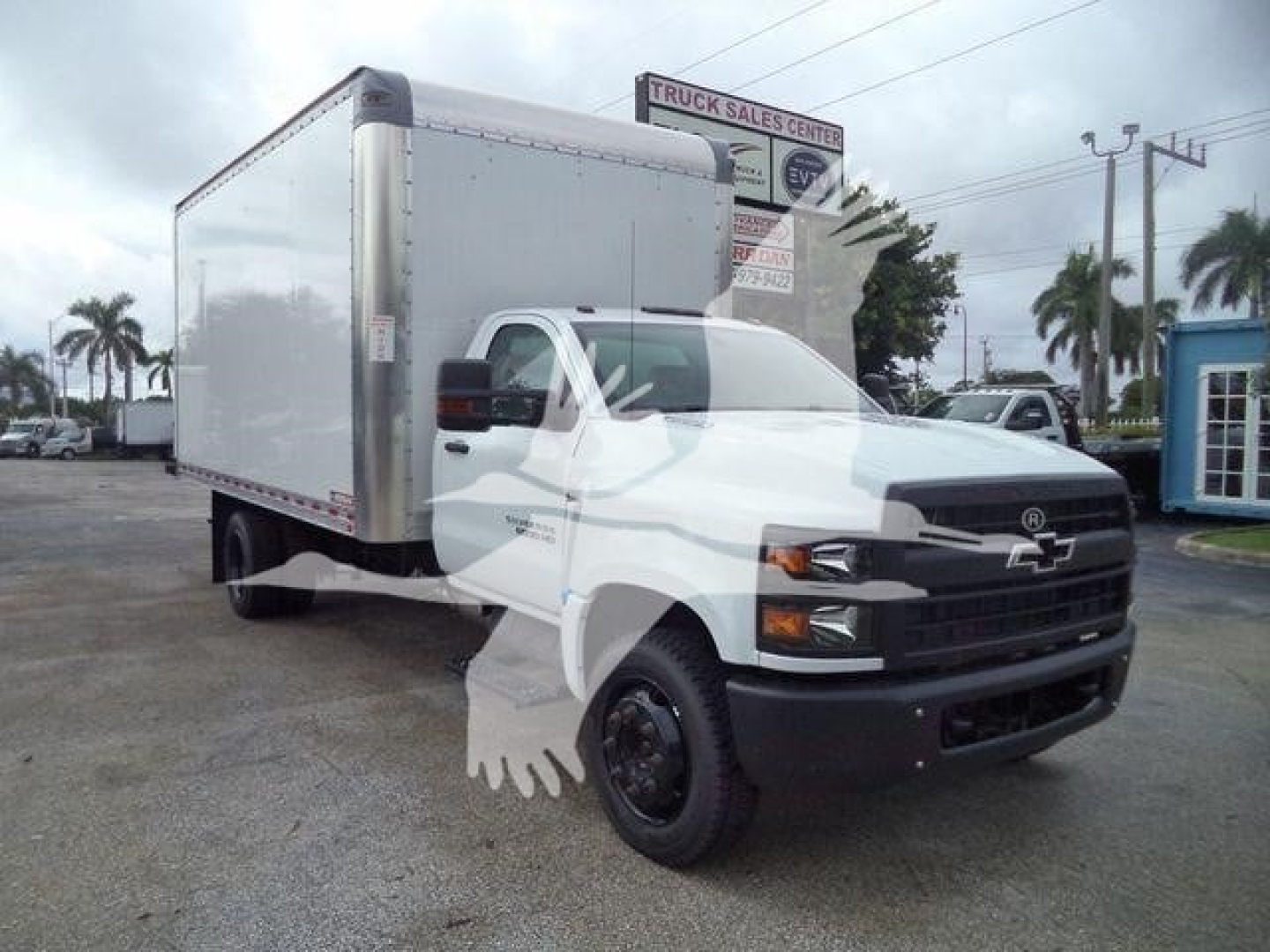 Box truck, white Chevrolet Silverado 6500HD with a large cargo box, front grille visible, stock image from dealership lot.