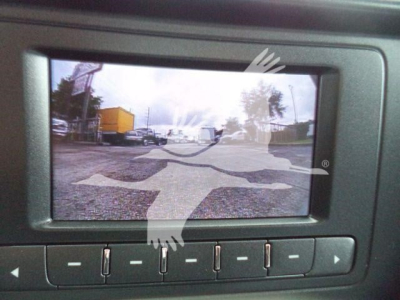 Rearview camera display showing a truck yard with a yellow trailer and other vehicles, Silverado 6500HD listing context text overlay.
