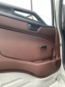 Cab door interior of a Hino L7 truck showing door panel with brown insert, window crank, handle, and armrest; no additional labels visible.