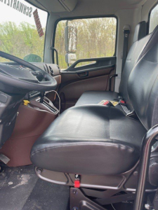 Truck cab interior showing front seat and dashboard of a Hino L7 cab chassis truck with black seats and brown trim.
