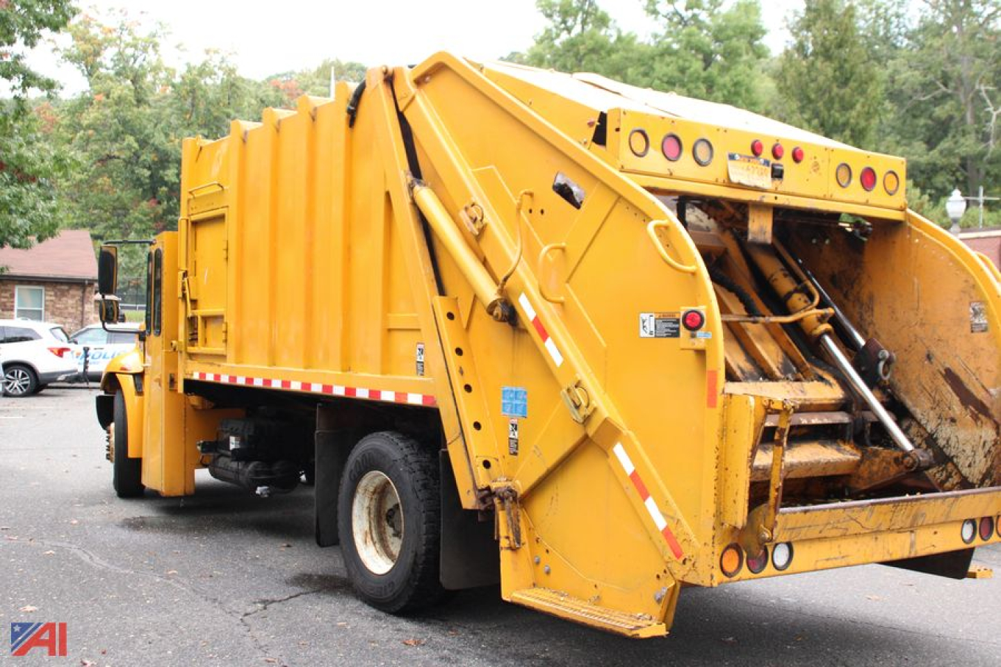 Rear view of a yellow International DuraStar 4300 packer truck showing the rear compactor and hydraulic arms.
