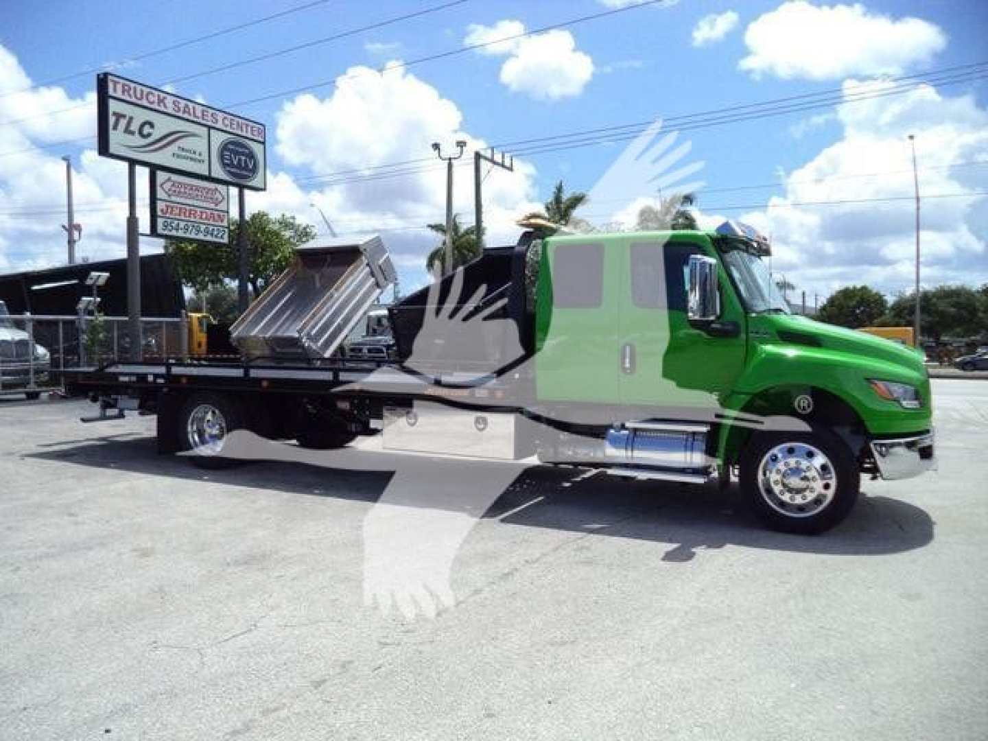 2026 International MV rollback truck with a green cab and a flatbed/dump bed in a dealership lot.