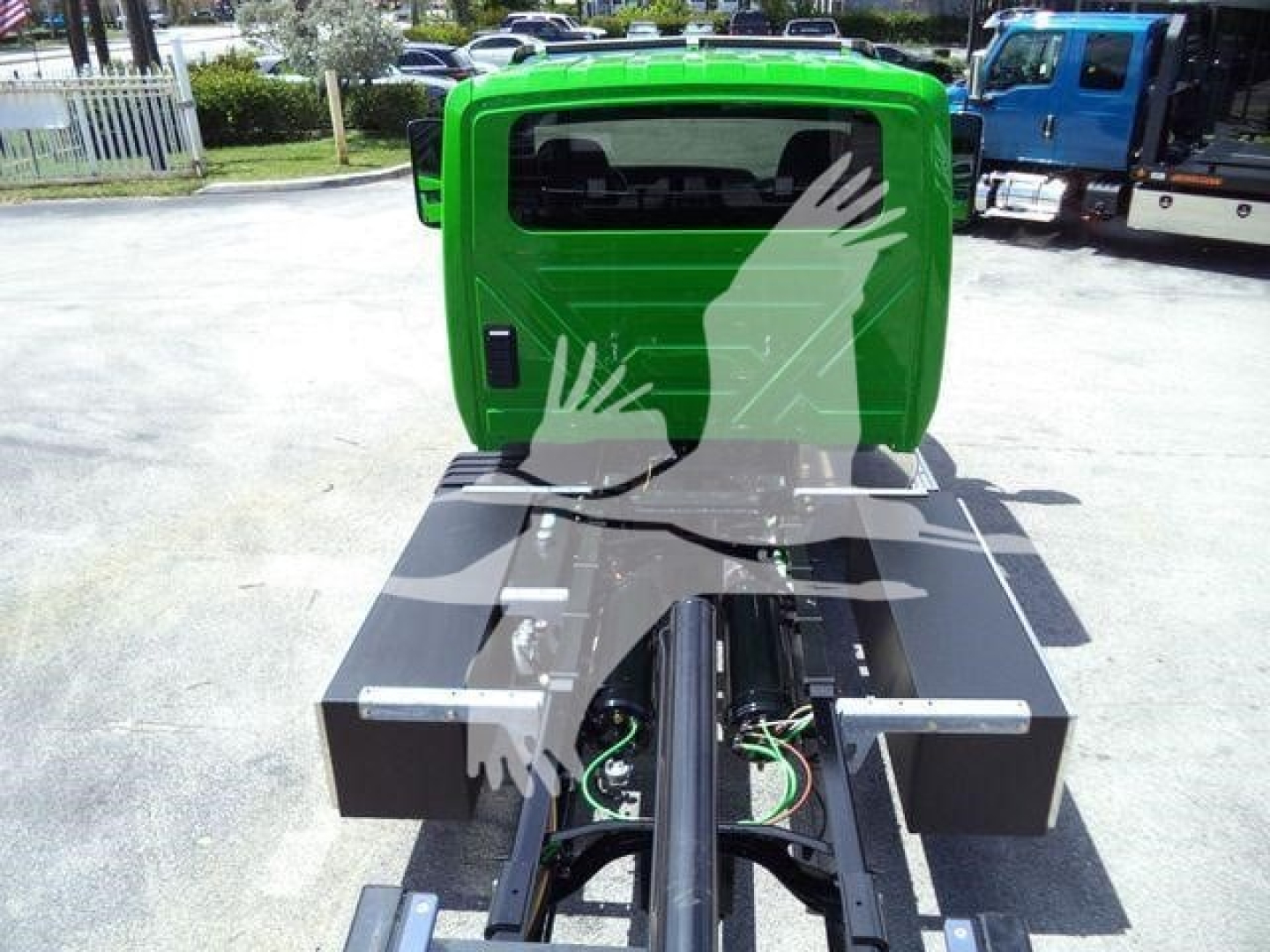 Green International MV rollback truck rear view showing hitch frame, hydraulic lines, and metal toolboxs on both sides