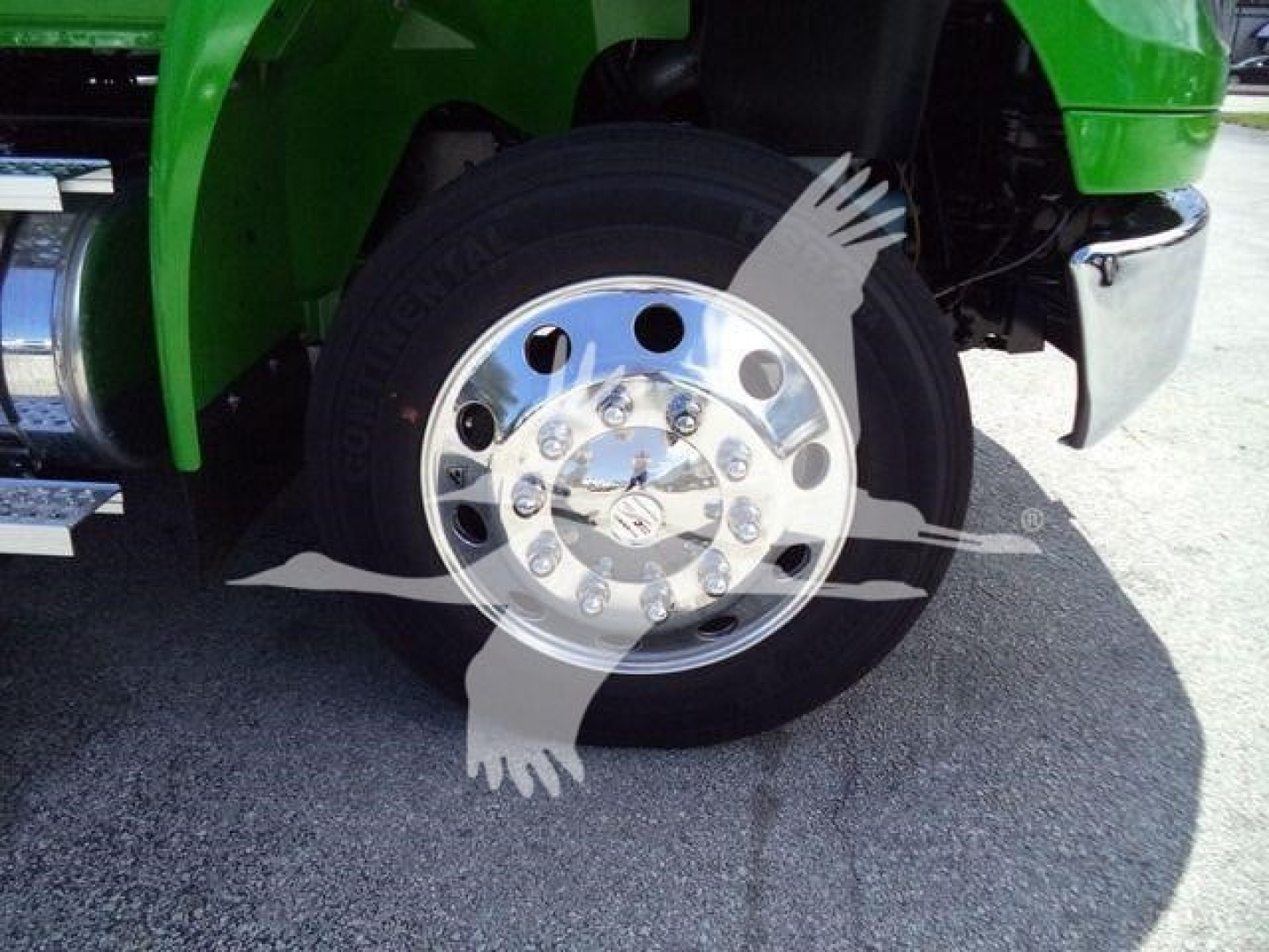 Truck wheel and chrome hubcap with green fender in a rollback truck.