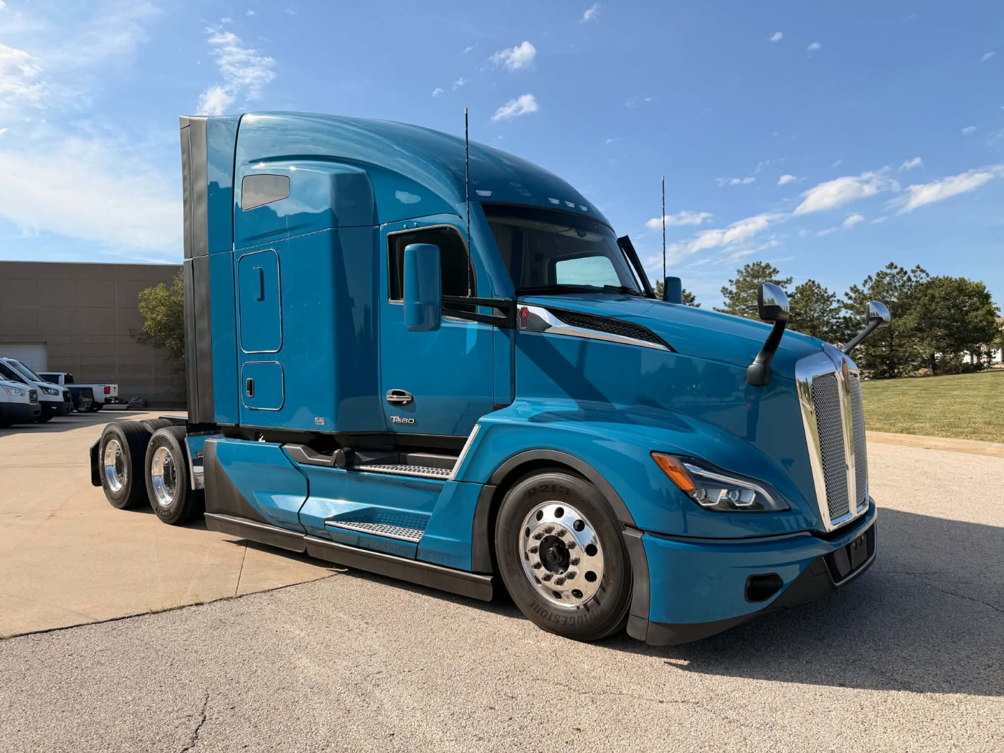 Kenworth T680 tractor in blue, side view showing cab, front grille, and aerodynamic design.