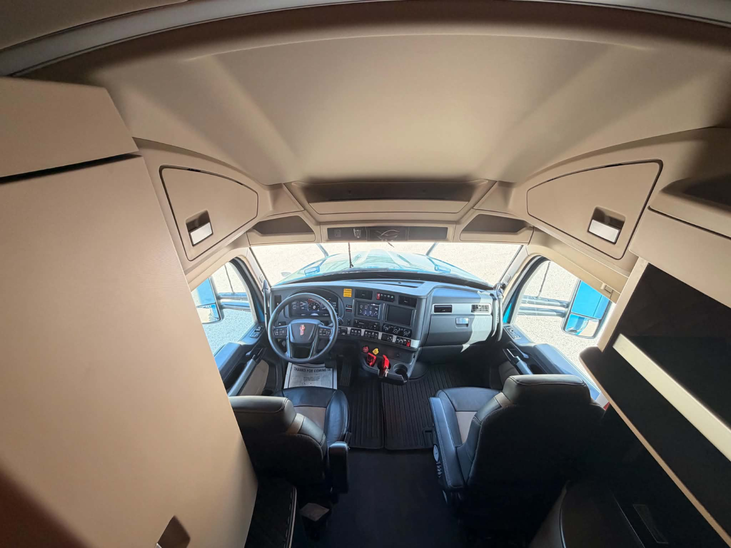 Kenworth T680 truck cab interior view from front seats, dashboard and steering wheel visible.