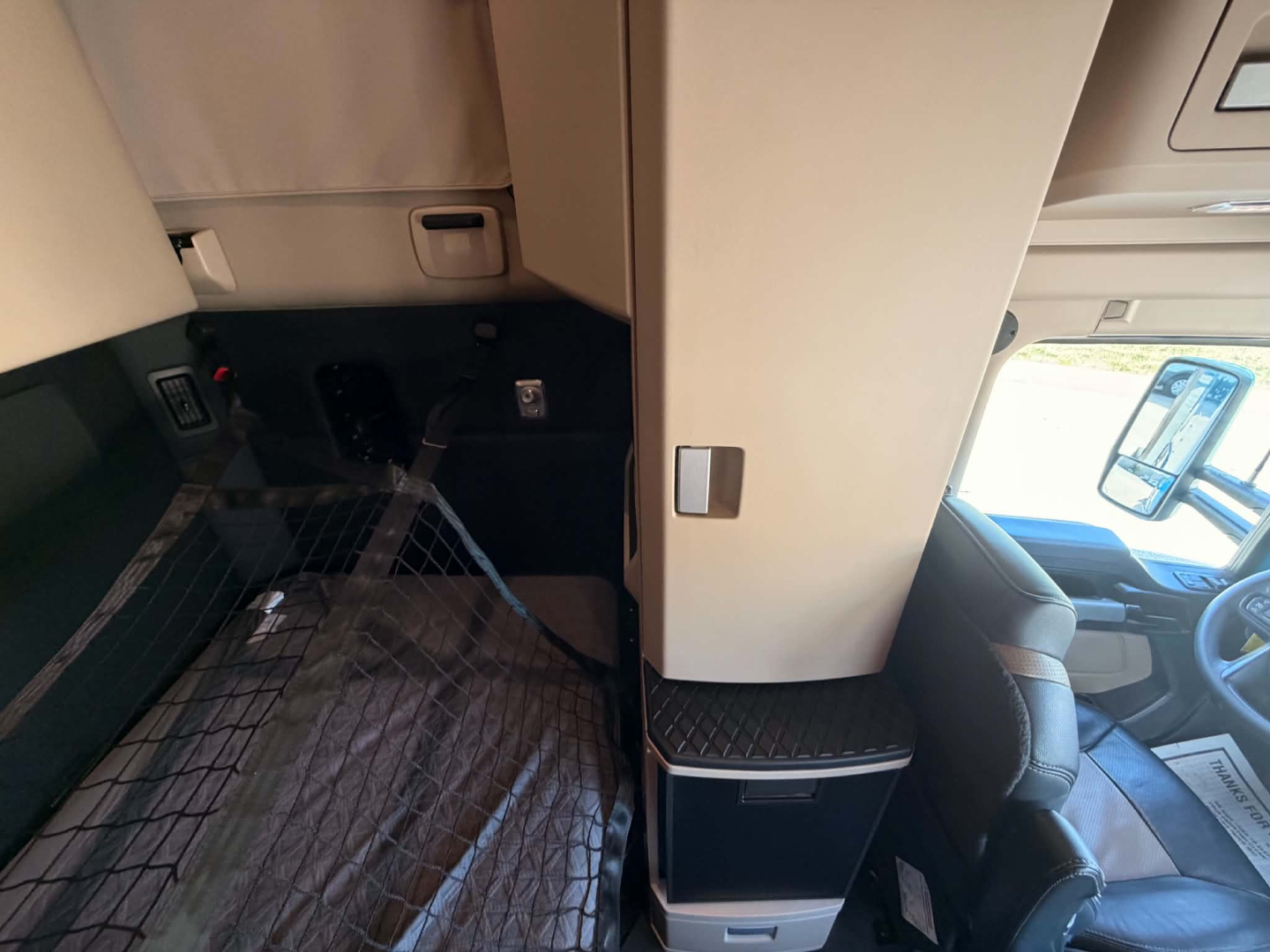 Kenworth T680 cab interior with driver seat and dashboard visible, floor mat and step area in view.