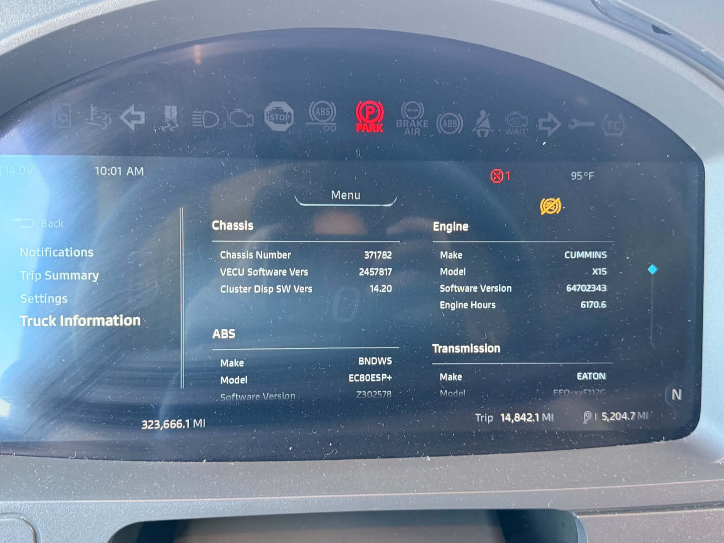 Kenworth T680 dashboard display showing chassis and engine information on the digital screen in a cab, including engine type Cummins and transmission info.