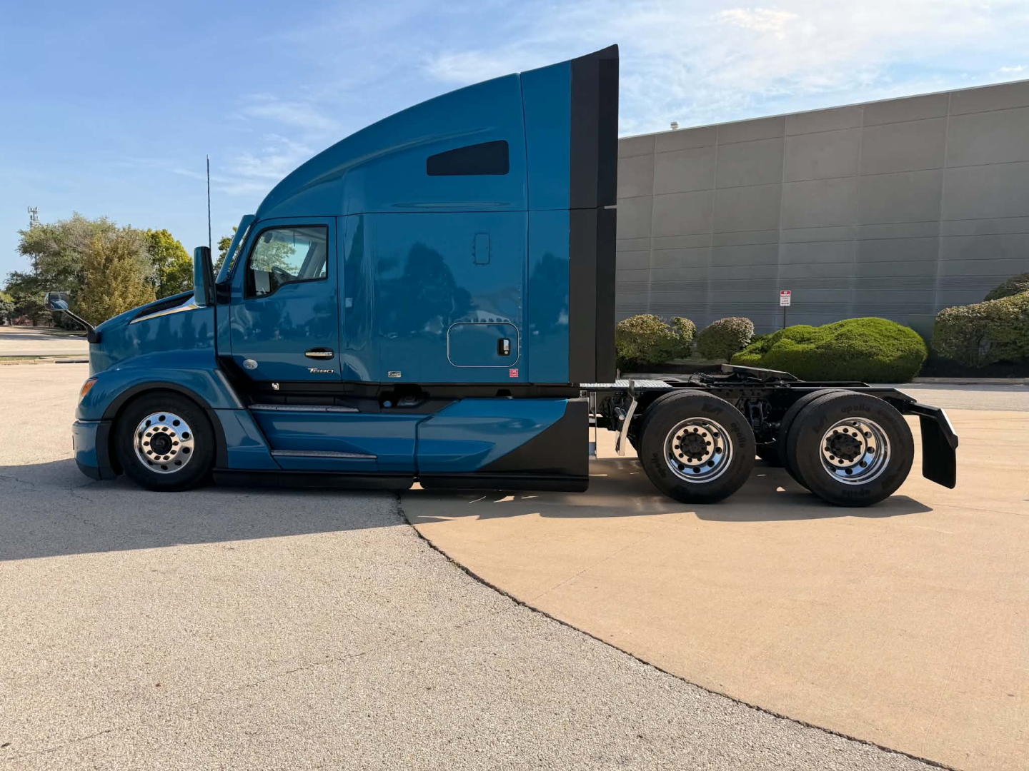 Kenworth T680 concrete sleeper truck side view showing blue cab with aerodynamic sleeper, rear dual axles, windows and side mirrors.