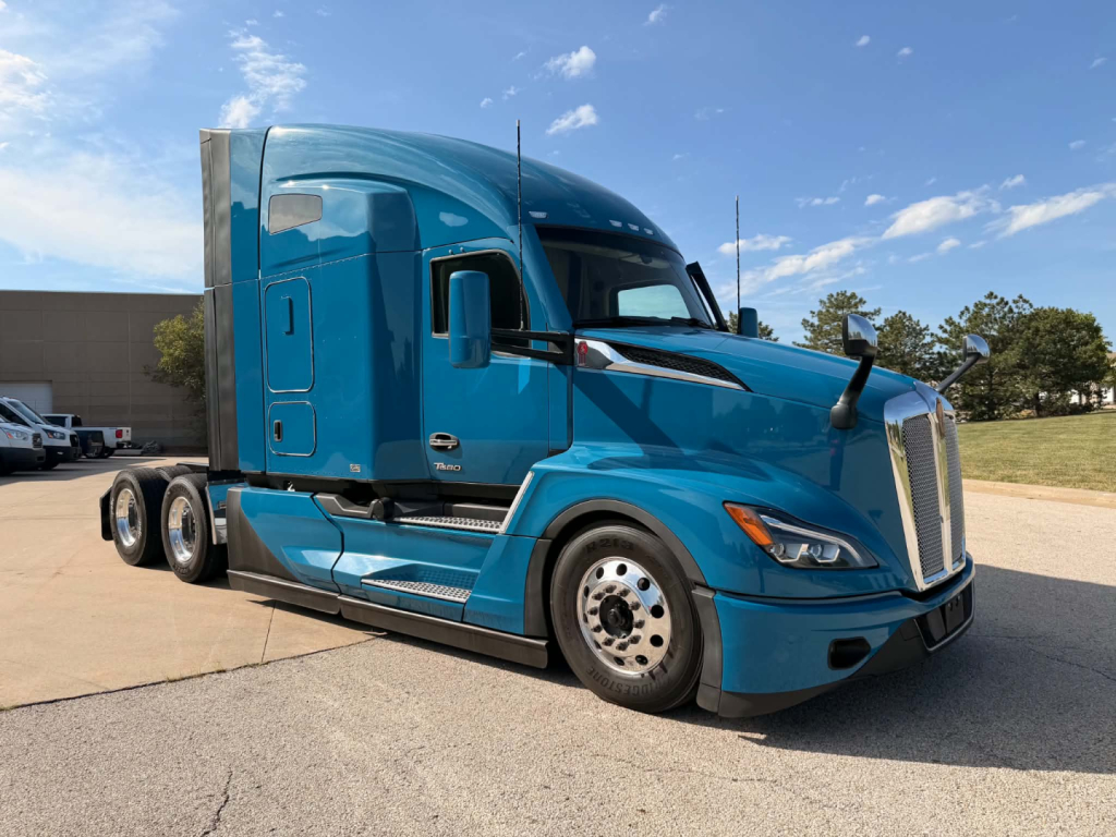 Kenworth T680 tractor in blue, side view showing cab, front grille, and aerodynamic design.