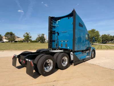 Kenworth T680 tractor in blue, side/rear view, showing sleeper cab and tandem rear axles with mud flaps.