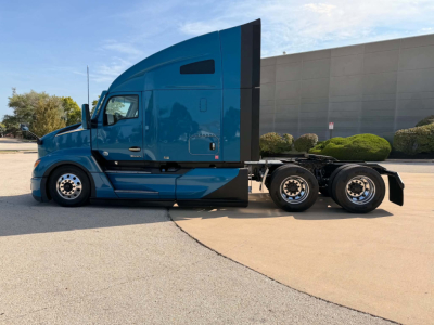 Kenworth T680 concrete sleeper truck side view showing blue cab with aerodynamic sleeper, rear dual axles, windows and side mirrors.