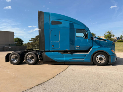Kenworth T680 sleeper cab truck side view showing blue exterior and rear triple axles.