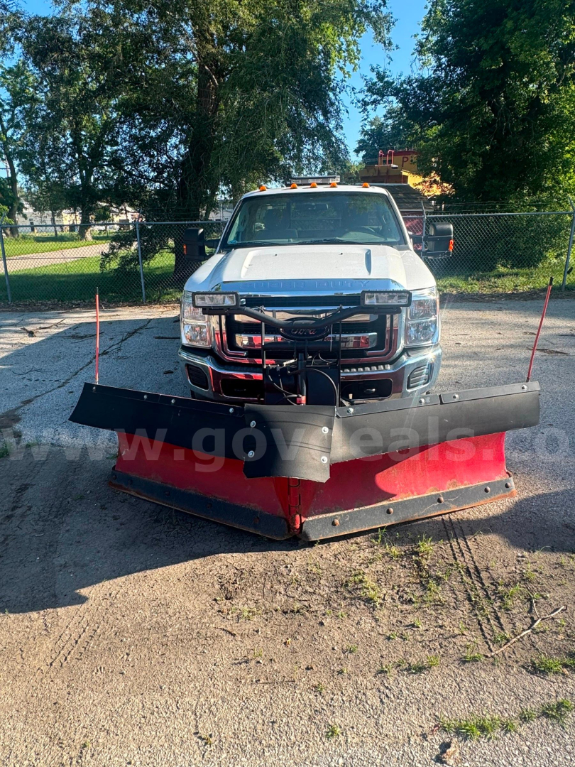 Ford F-350 pickup truck with a large red snow plow attached in front, service/utility truck, white cab, daytime outdoor lot.