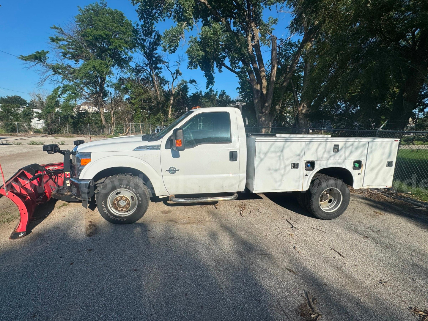 Ford F-350 utility truck with a service bed and snow plow mount, side view showing stock utility compartments and dual rear wheels.