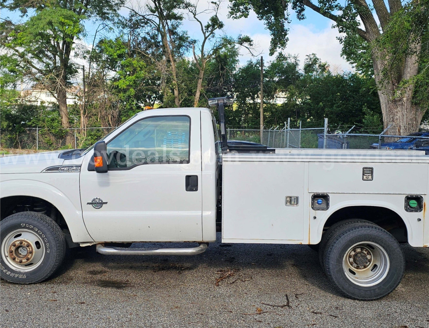 Ford F-350 utility pickup side view showing service body with compartments and rear wheel; cab and side mirror visible.
