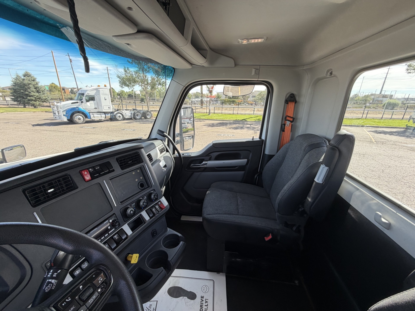 Cab interior of a 2023 Kenworth T880 conventional daycab showing dashboard with control panel, steering wheel, driver seat, and passenger seat.