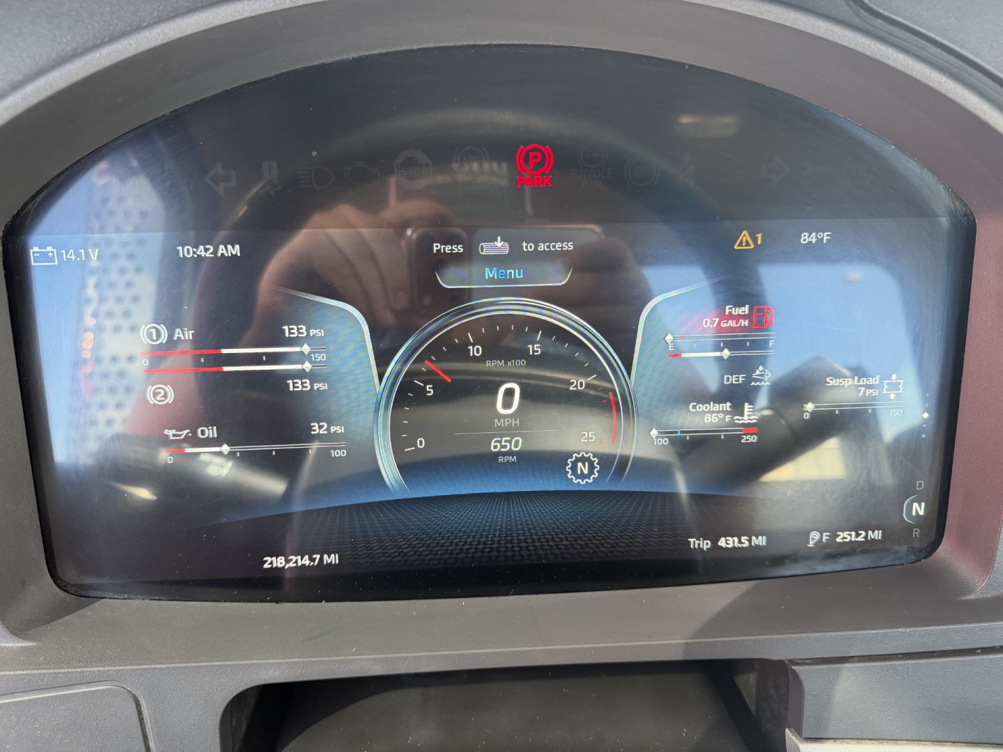 Digital dash display showing speedometer at 0 mph, fuel, oil, coolant, DEF gauges, and warning icons in a Kenworth T880 cab.