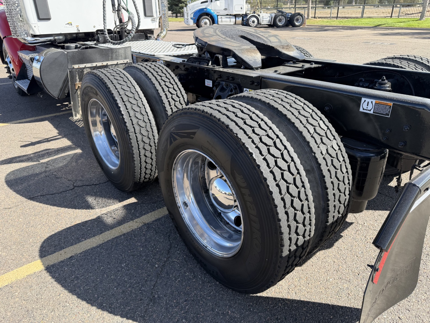 Kenworth T880 chassis with dual rear axles showing tires and wheels in a truck lot.