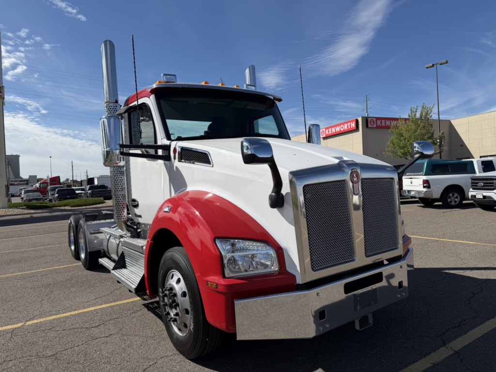Kenworth T880 conventional daycab truck in white and red with chrome grille and dual exhaust stacks, front view in parking lot.