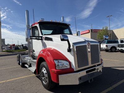 Kenworth T880 conventional daycab truck in white and red with chrome grille and dual exhaust stacks, front view in parking lot.