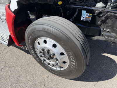 Kenworth T880 front wheel shown with tire and wheel well, partial engine bay visible and warning label on radiator area.