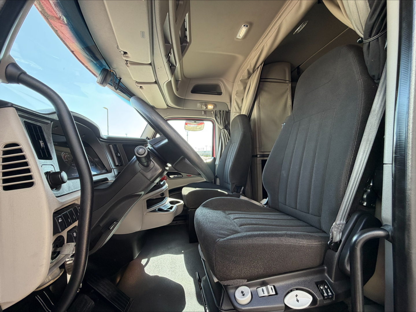 Peterbilt 579 truck cabin interior showing driver seat, dashboard, steering wheel, and entry area.