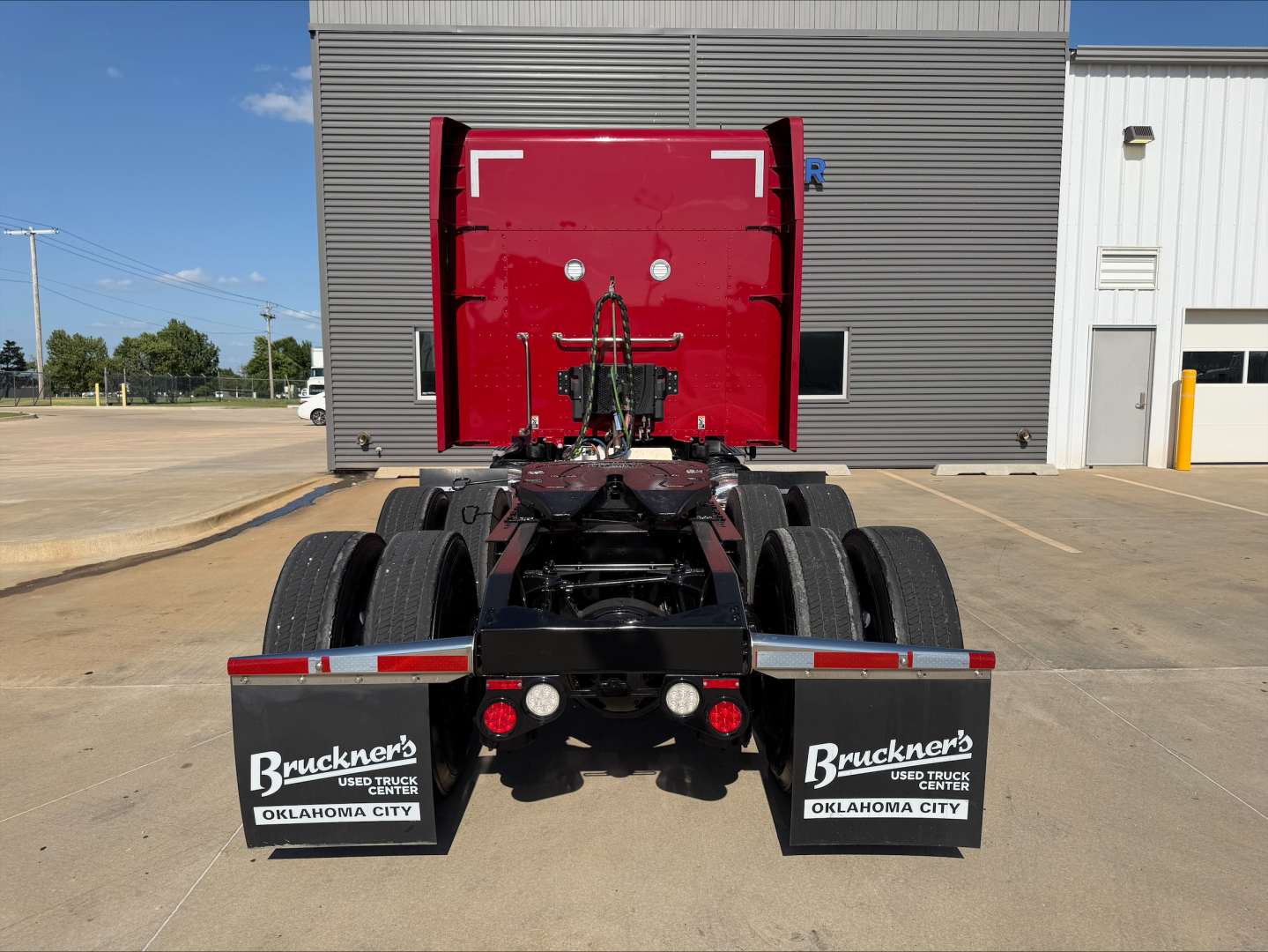 Peterbilt 579 rear view showing chassis and dual rear axles, red cab, mud flaps with Bruckner's Used Trucks Oklahoma City branding.