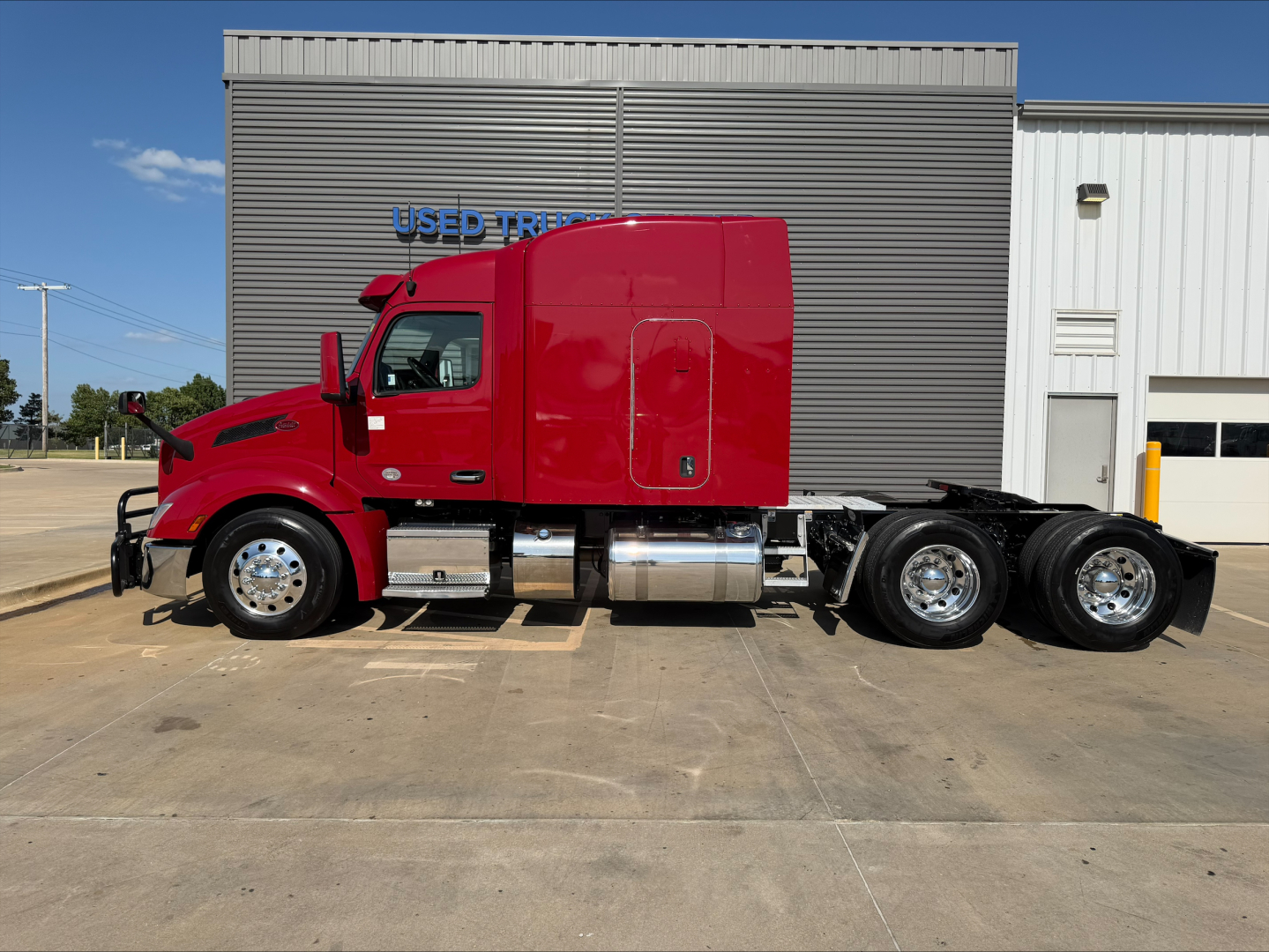 Peterbilt 579 tractor in red, side view, with dual rear axles, chrome fuel tanks, and cab accessories.