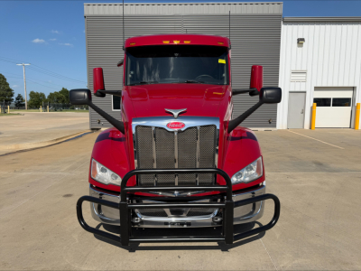 Peterbilt 579 front view with black grille guard, red cab, large chrome grille, silver bumper, and black mirrors.