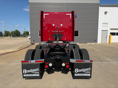 Peterbilt 579 rear view showing chassis and dual rear axles, red cab, mud flaps with Bruckner's Used Trucks Oklahoma City branding.