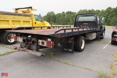 Flatbed chassis truck back view showing heavy-duty trailer bed with dual rear wheels and taillights.