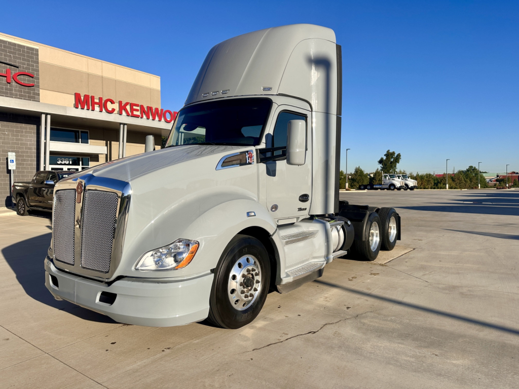 Kenworth T680 tractor unit in front of dealership showing aerodynamic sleeper cab and dual rear axles.