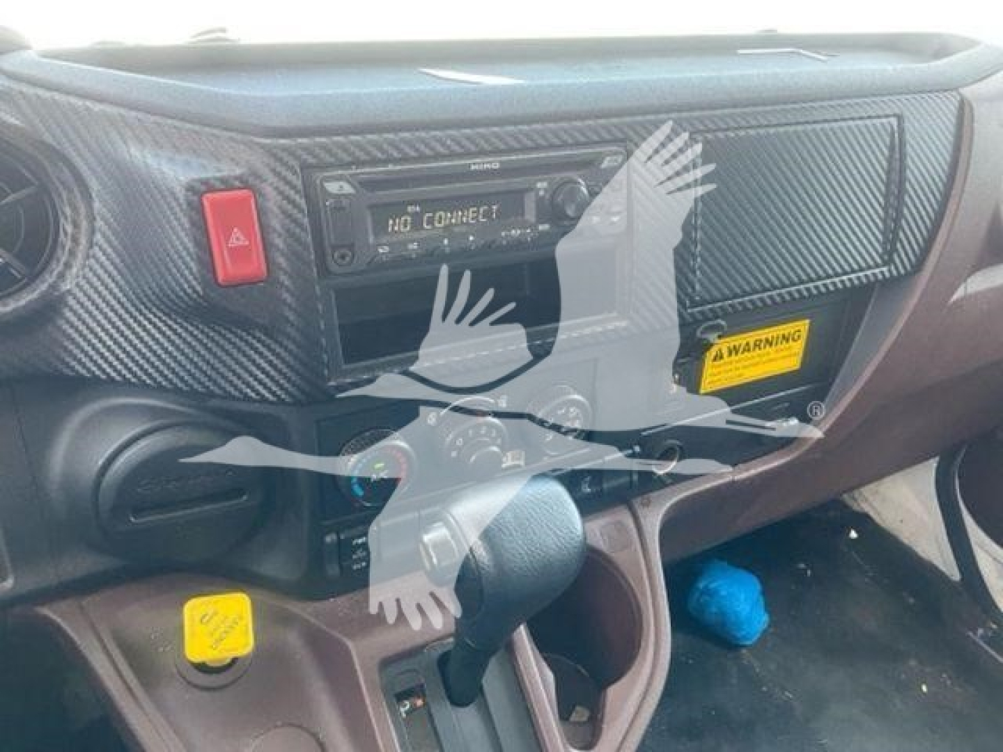 Interior dashboard of a 2023 Hino L6 box truck showing a radio head unit, control buttons, and a steering column with a textured dashboard cover.