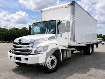 White Hino box truck with cargo box and cab, front three-quarter view in a parking lot.
