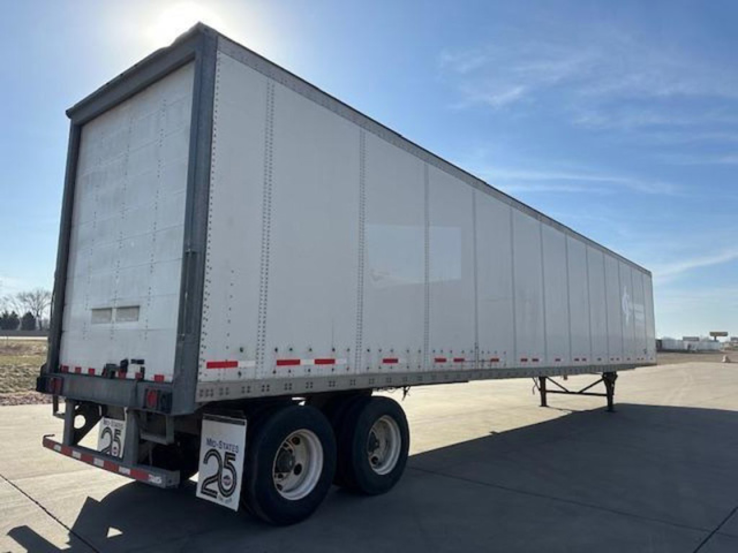 Wabash dry van trailer showing side view with white aluminum panels and dual rear wheels.