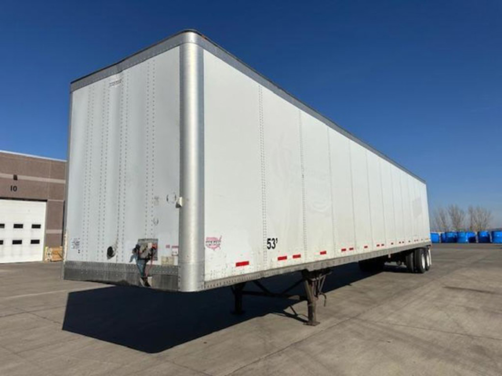 Trailer body showing a white Wabash van trailer with front hitch and tandem rear wheels, side detailing and reflector lights.