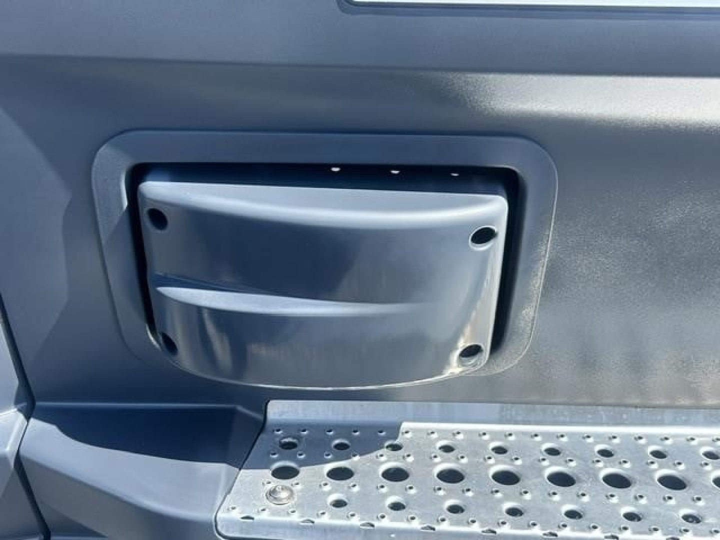 Freightliner Cascadia 126 cab interior showing a small recessed storage/step area with a molded cover and perforated metal step surface.