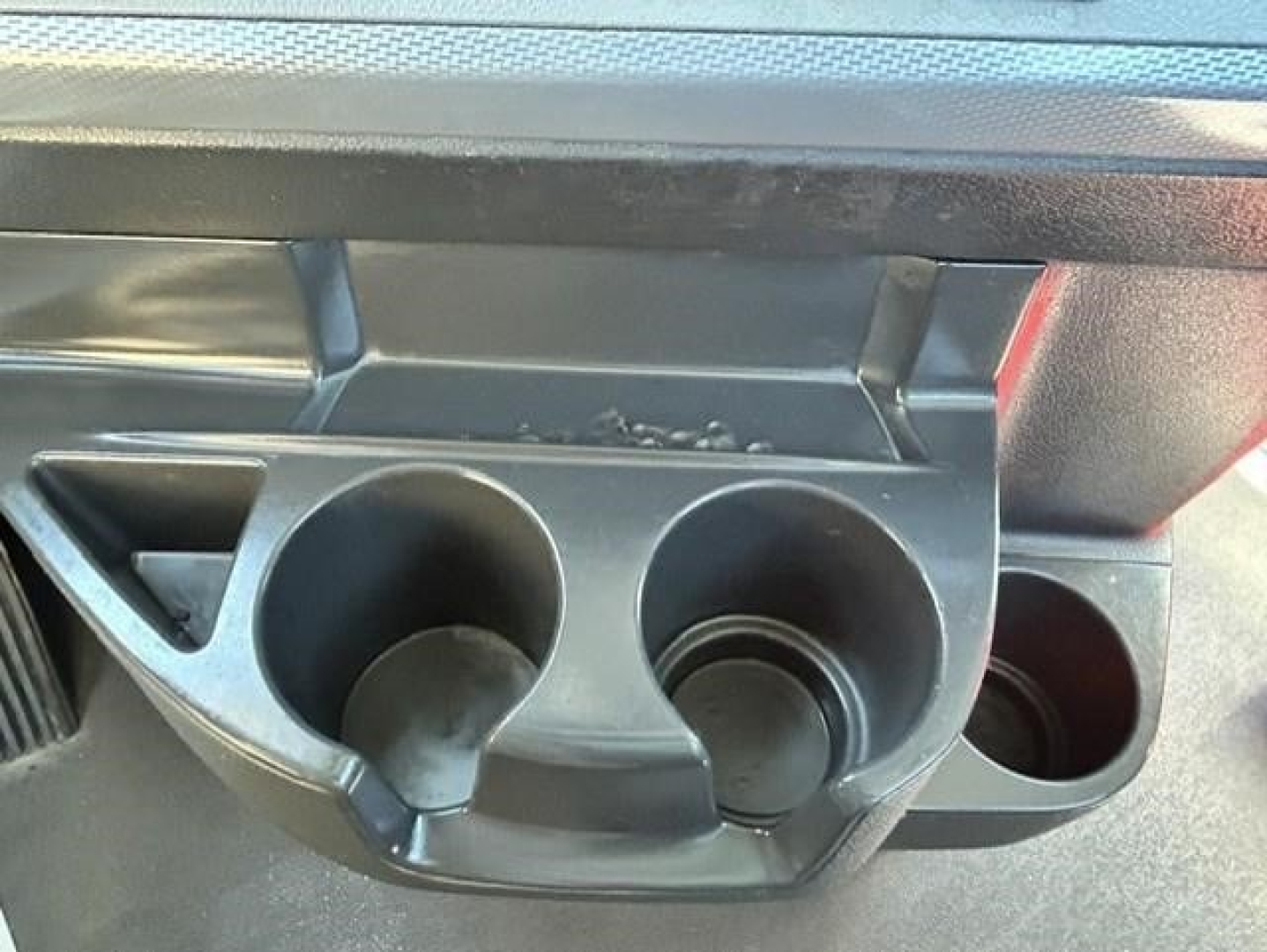 Cupholder area with two round drink holders and a smaller slot, in a Freightliner Cascadia 126 interior view.