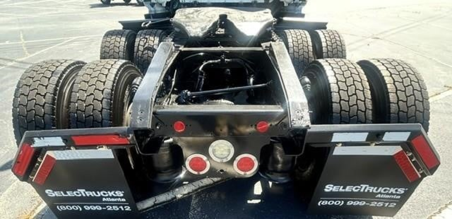 Freightliner Cascadia rear chassis showing dual rear axles and fifth-wheel mount, with mudflaps reading SelectTrucks, tail lights, and warning lights.