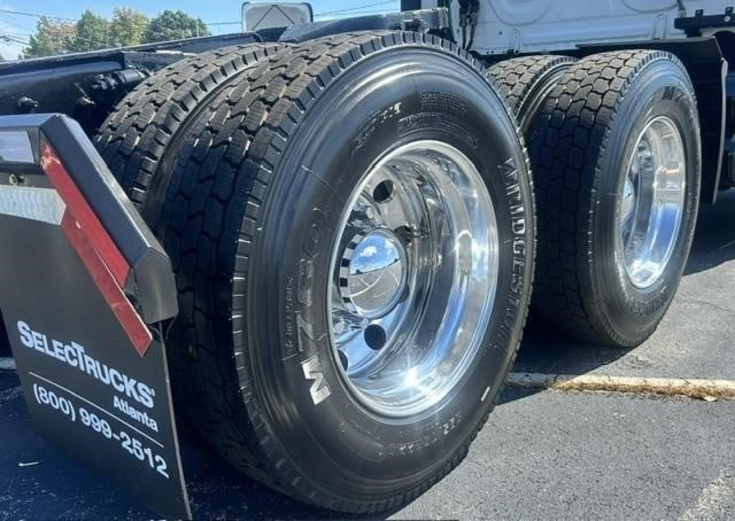 Freightliner Cascadia 126 tandem rear wheels showing dual tires and polished rims with side mud flap and wheel rims.