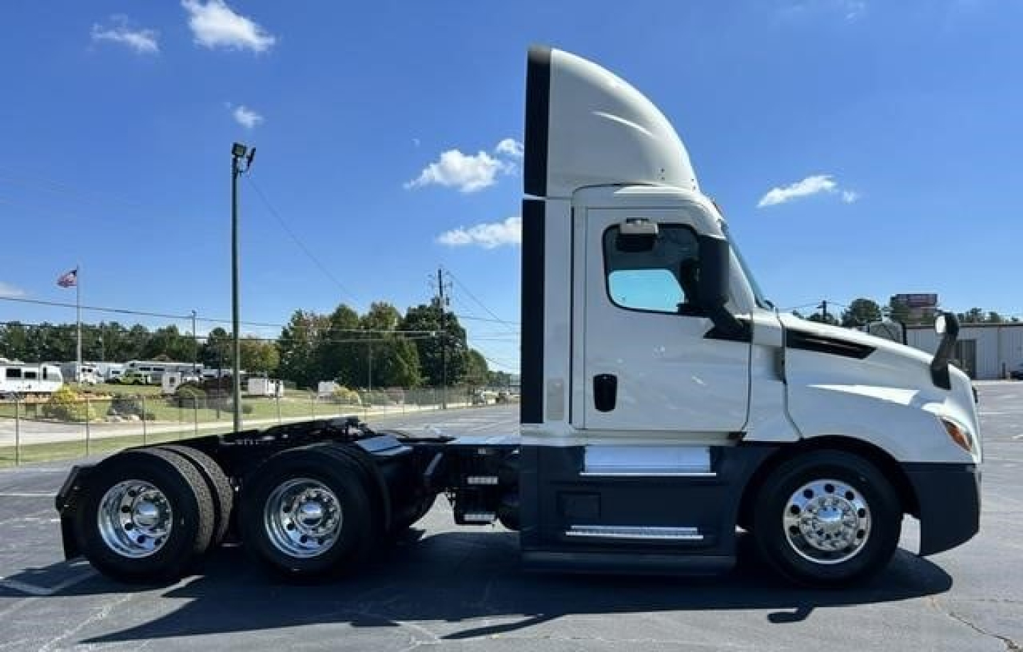 Truck side view showing 3-axle Freightliner Cascadia 126 sleeper cab with white exterior and black chassis.