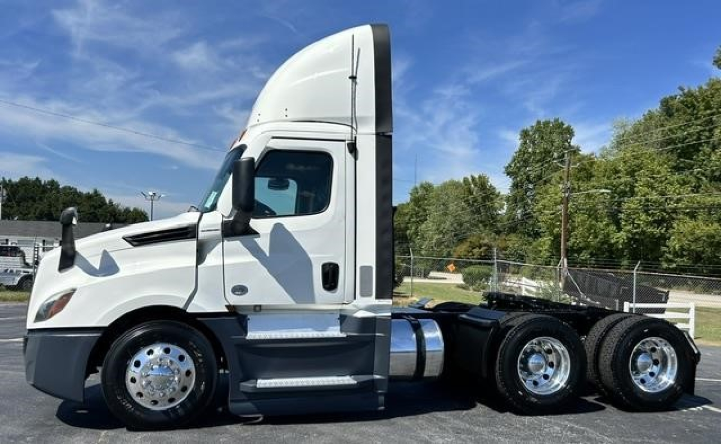 Freightliner Cascadia 126 day cab truck side view showing front wheel area and sleeper cab with chrome wheels.