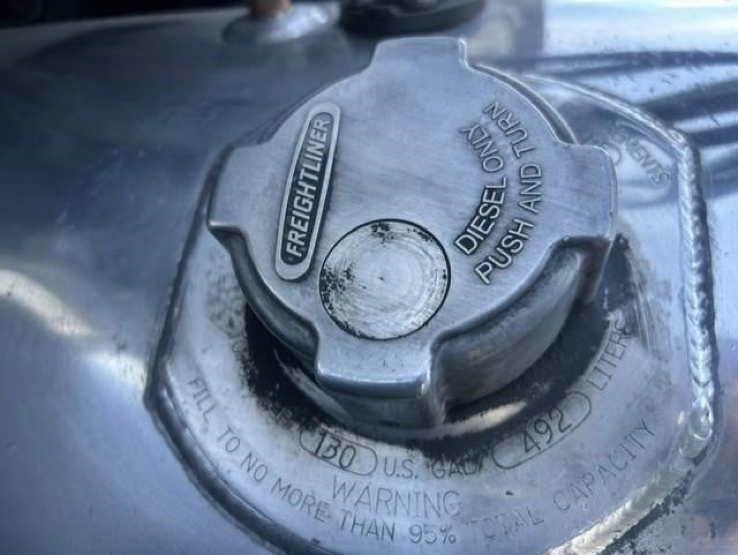 Diesel fuel cap on Freightliner Cascadia fuel tank shows 'FREIGHTLINER' and 'DIESEL FUEL ONLY' markings with warning text embossed around cap.