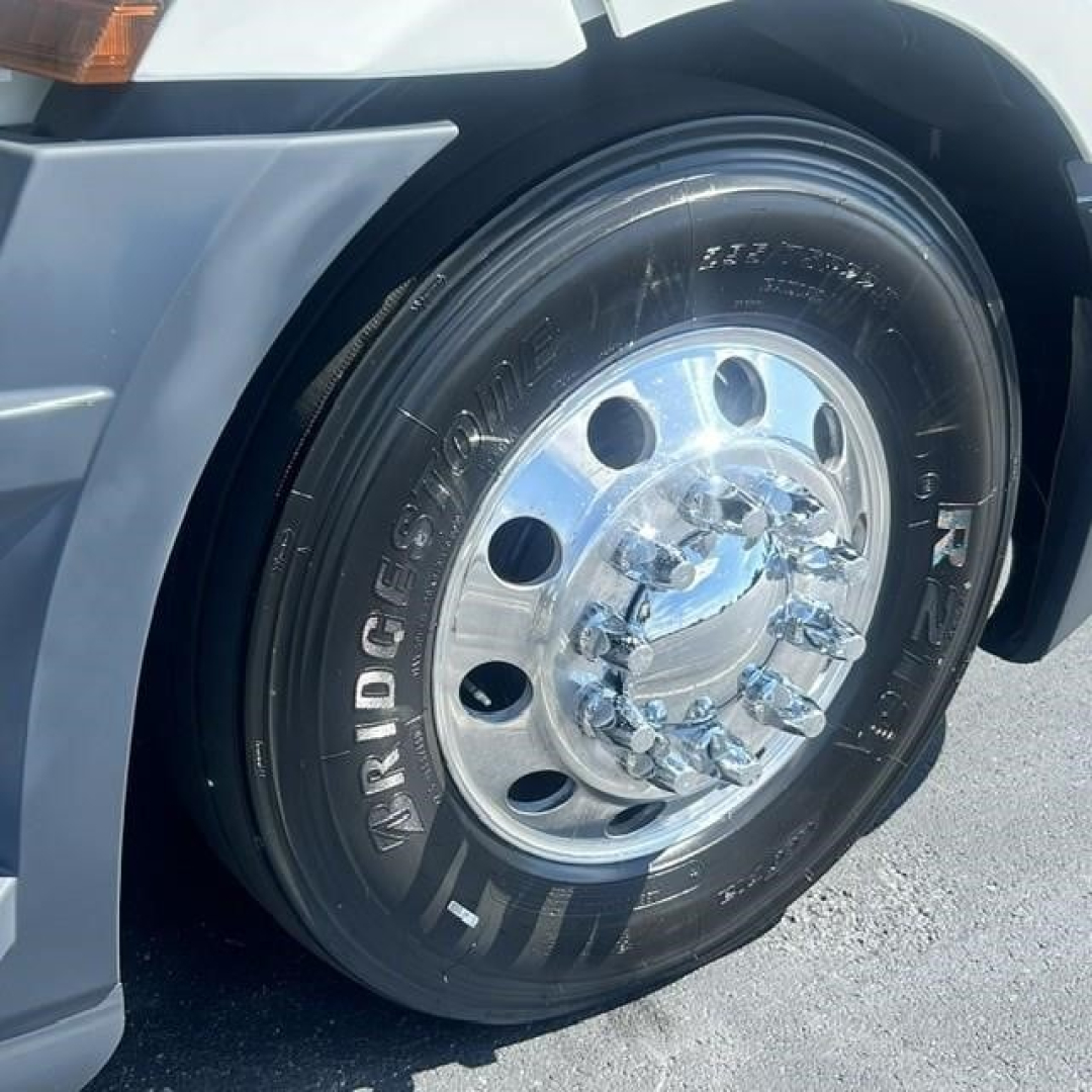 Truck wheel of a 2022 Freightliner Cascadia 126 showing Bridgestone tire and shiny chrome hubcap; partial fender and wheel well visible.