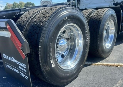 Freightliner Cascadia 126 tandem rear wheels showing dual tires and polished rims with side mud flap and wheel rims.