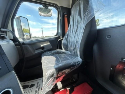 Seat in truck cab with plastic covers, steering wheel, and window; Freightliner Cascadia interior visible.