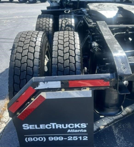 Rear view showing dual rear axles of a Freightliner Cascadia truck chassis with tires and hitch, SelectTrucks Atlanta plate visible.